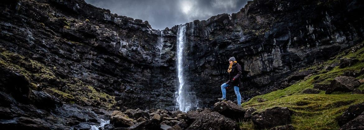girl hiking in front of Fossa waterfall in Faroe Islands