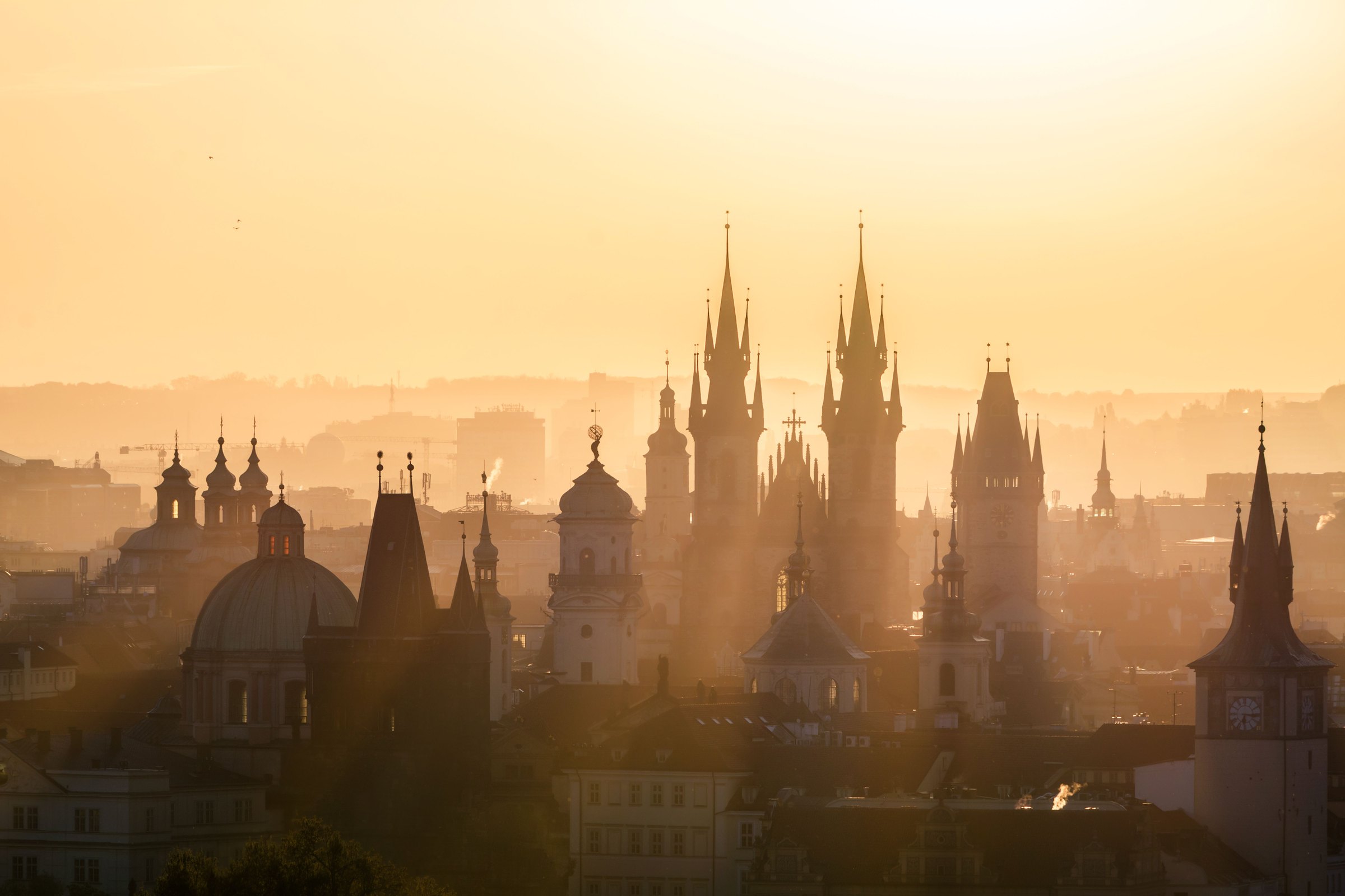 Spires of Prague's Old Town silhouetted in golden morning haze