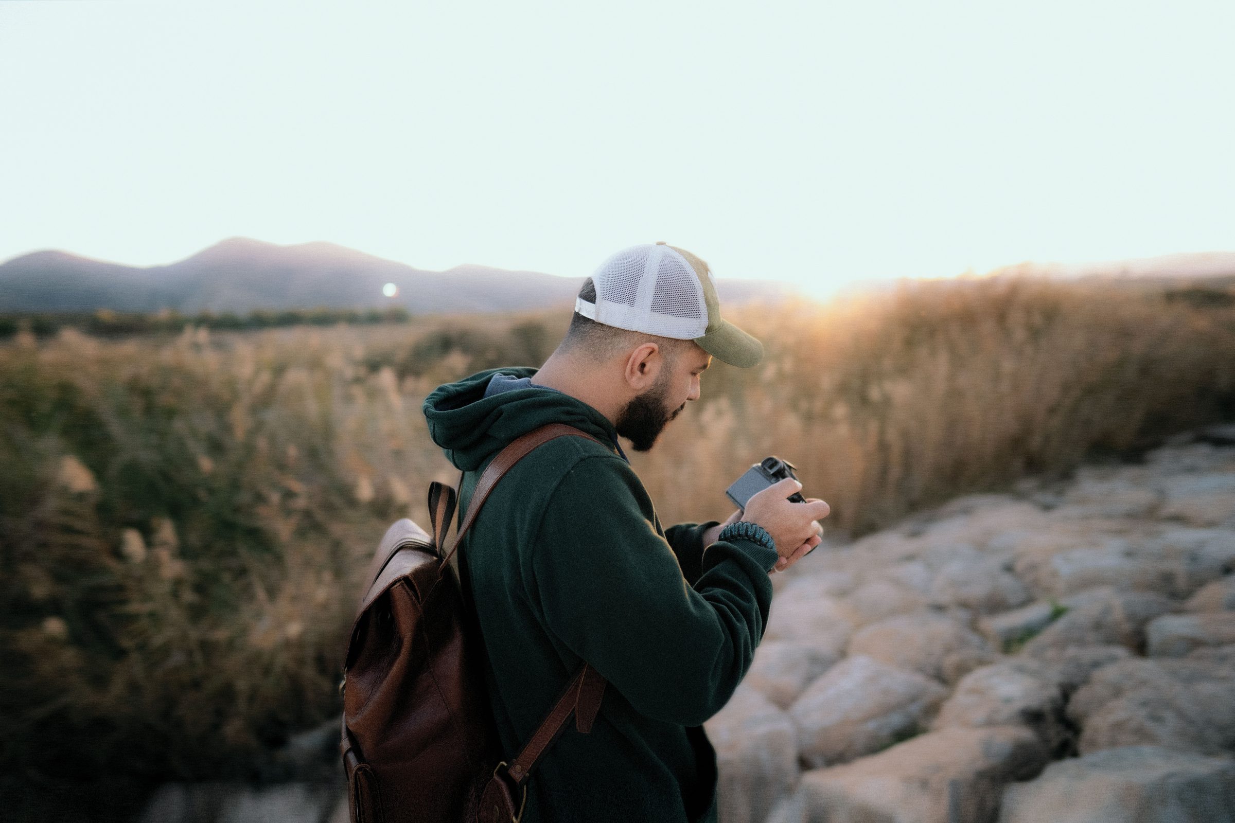 Hiker checking the pictures on the back of a camera at sunset