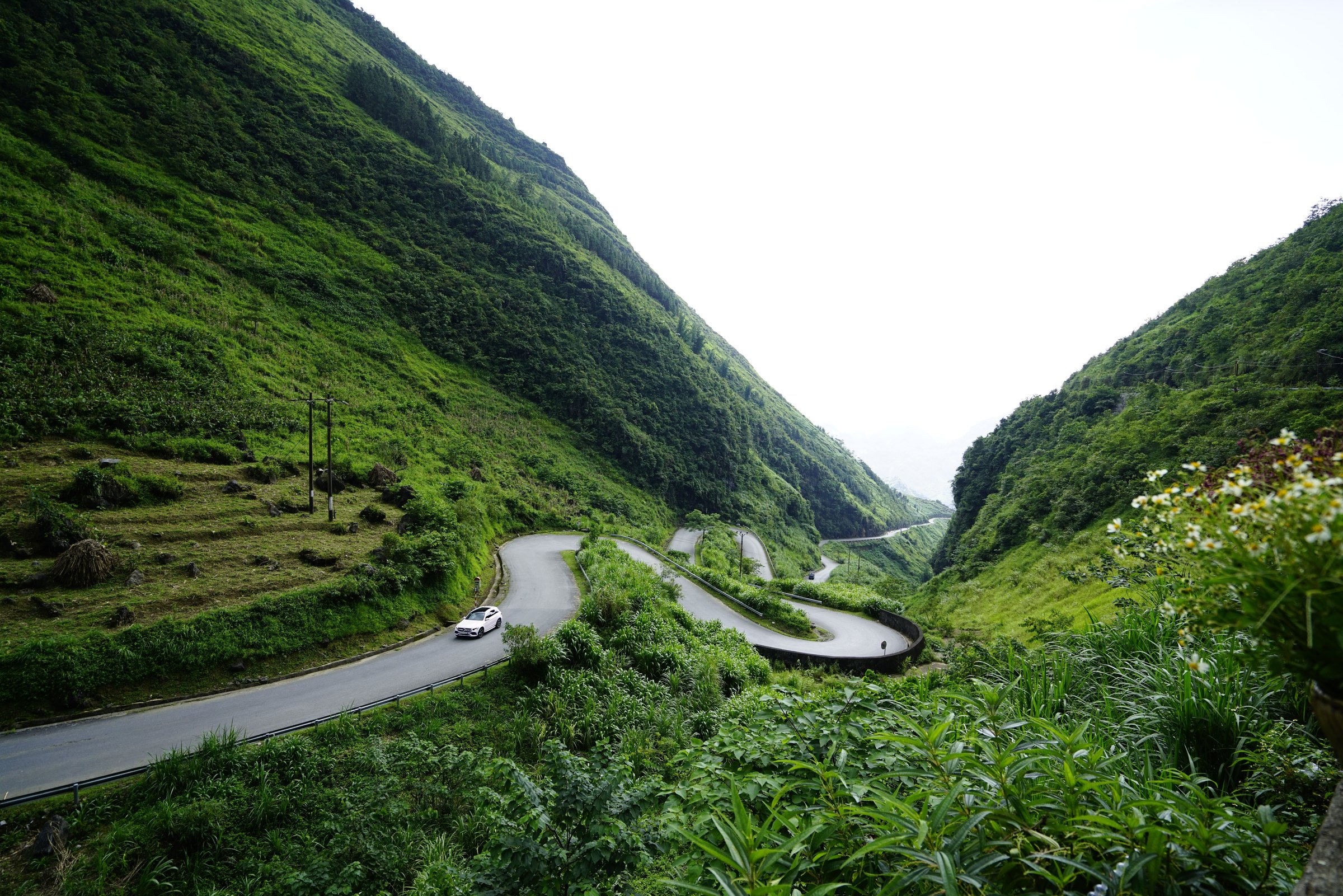 Mountain road winding through a green valley in Ha Giang, Vietnam