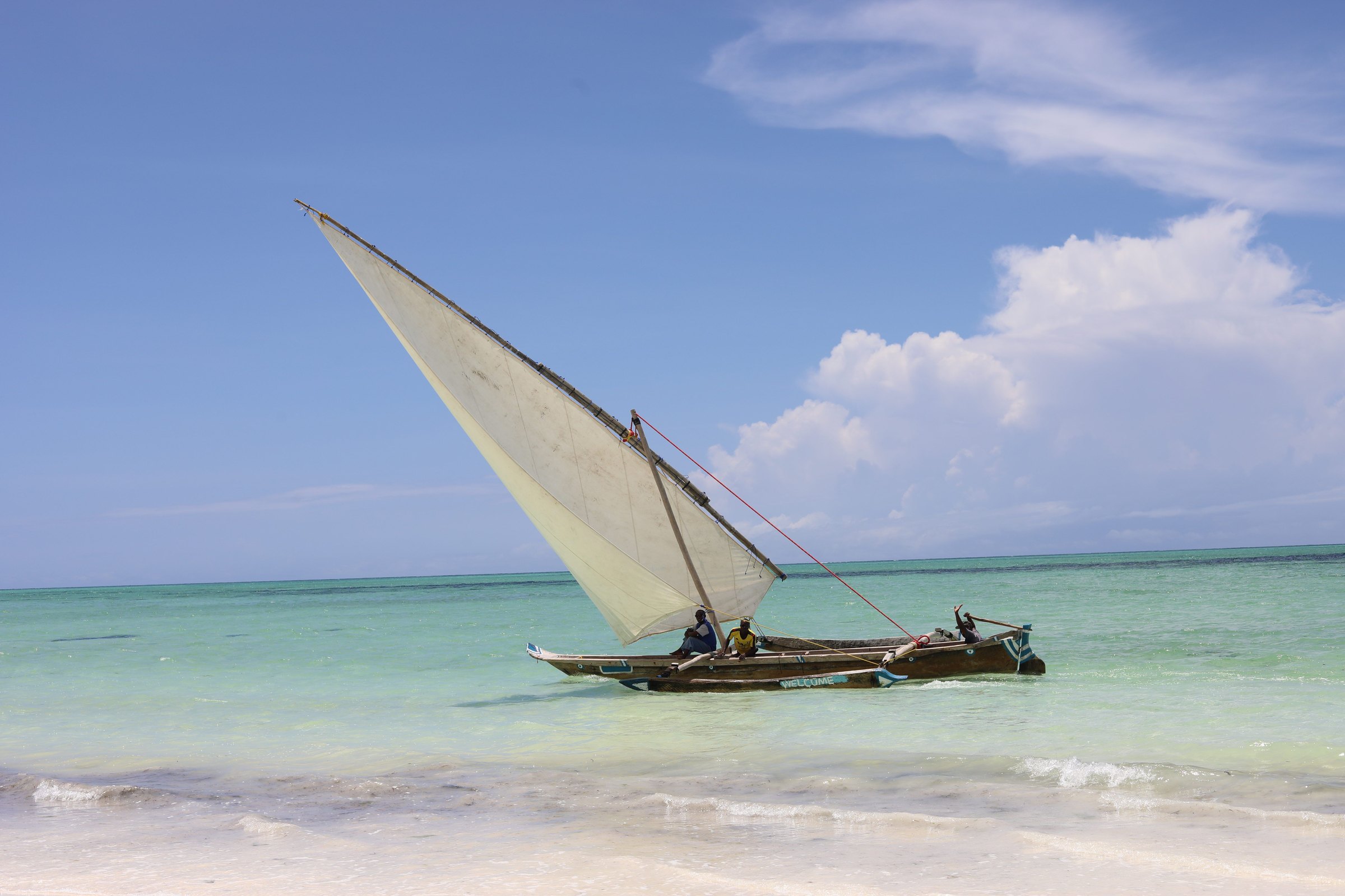 Traditional dhow under sail in the turquoise shallows off Zanzibar